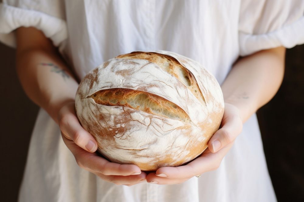 Woman hand holding a round loaf of bread person human food.