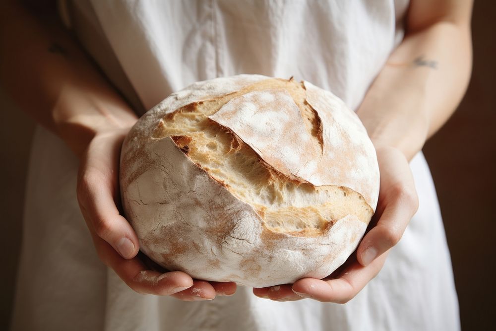 Woman hand holding a round loaf of bread person human food.