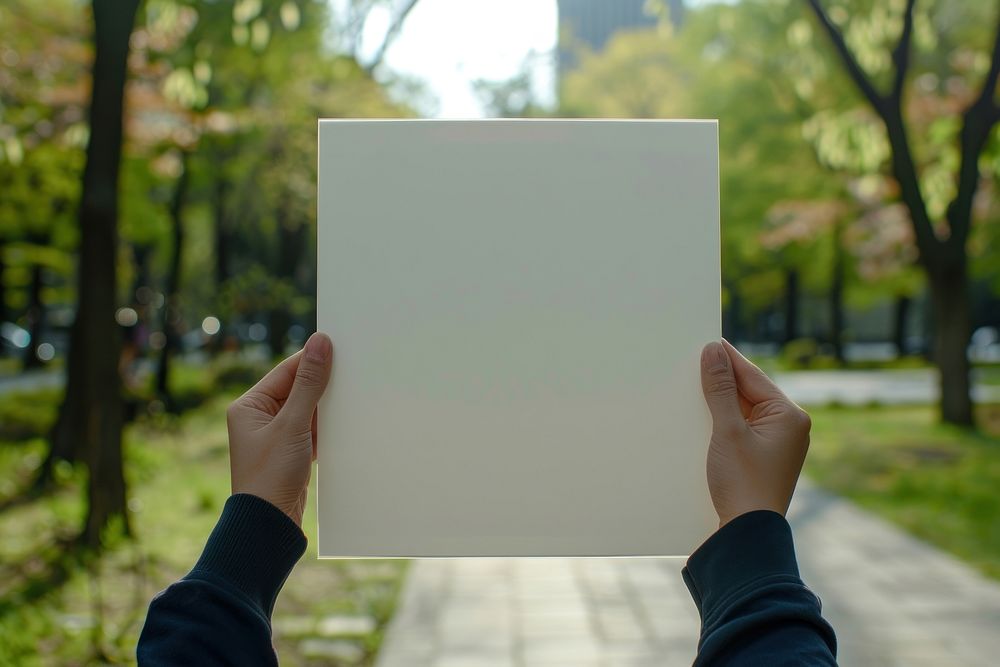 Hand holding blank square paper cover album vinyl record against park photo photography electronics.