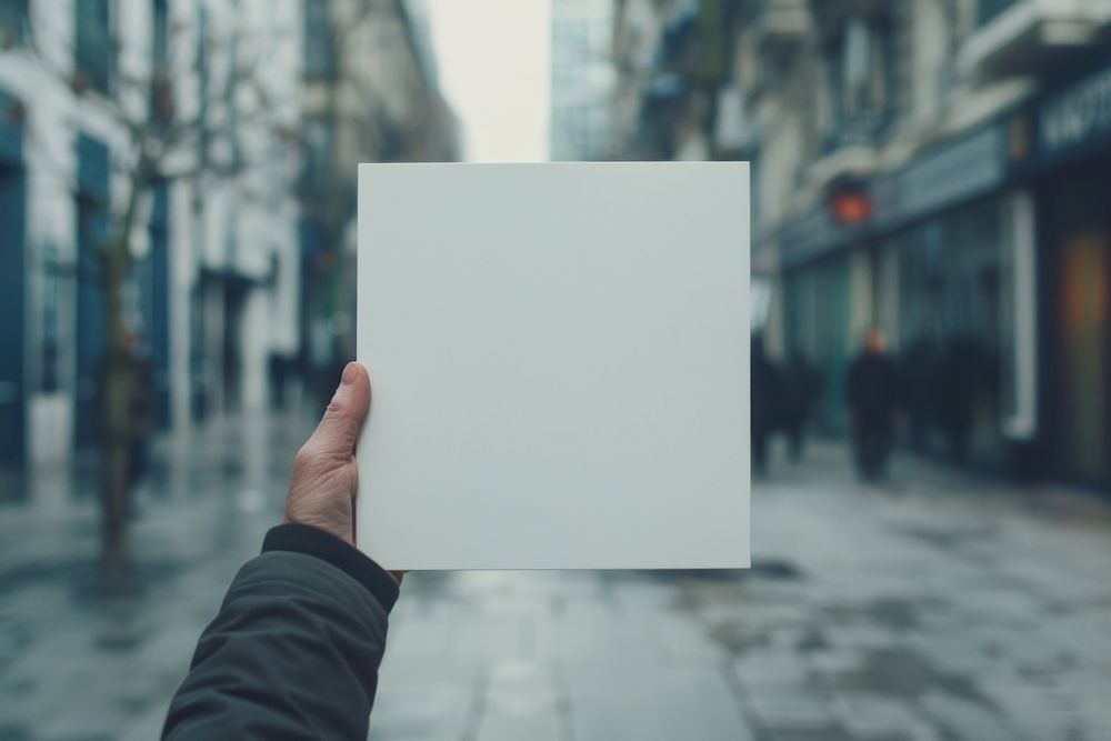 Hand holding blank square paper cover album vinyl record against mall photo advertisement photography.