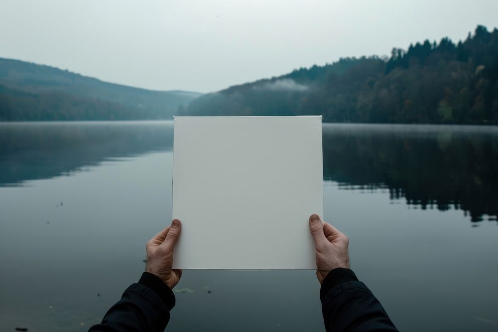 Hand holding blank white square paper cover album vinyl record against lake outdoors photo photography.