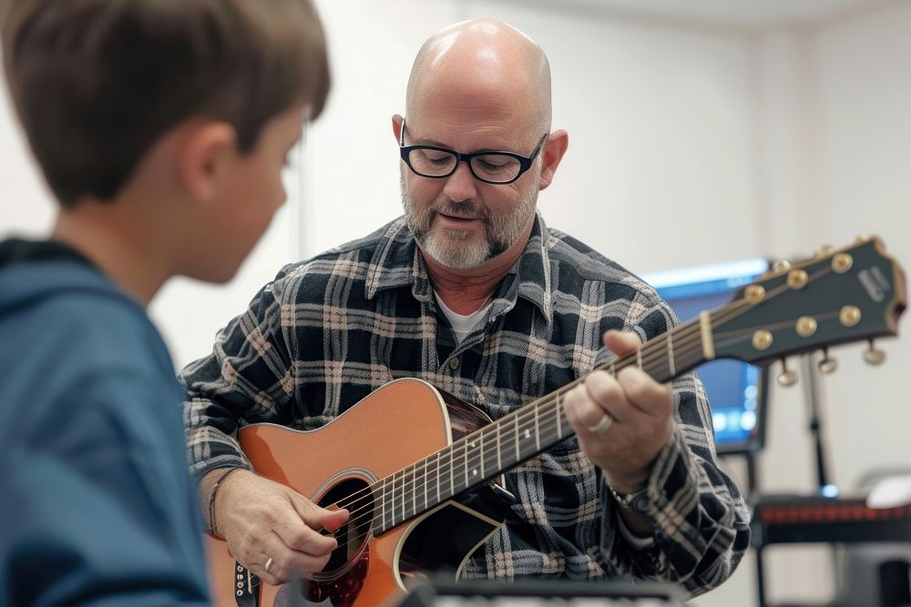 Teacher teaching boy playing guitar at music classroom accessories electronics recreation.