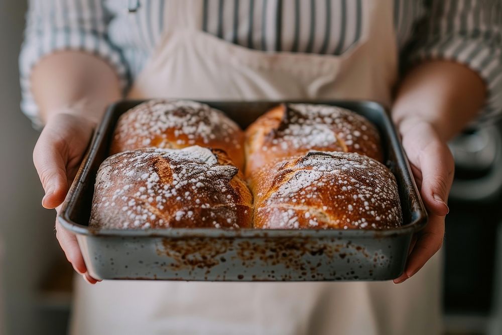 Woman hands hold a baking tray of 2 fresh baked sourdough person bread human.