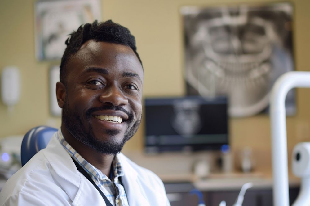 A black man dentist smile aganist dental electronics hardware monitor.