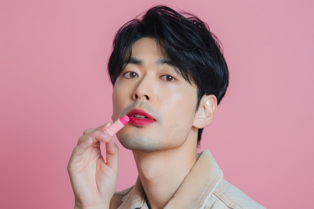 Asian transgender male hand holding pink lipstick with confident pose cosmetics person human.