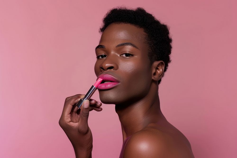 Black transgender male holding and apply pink lipstick with confident pose cosmetics person makeup.