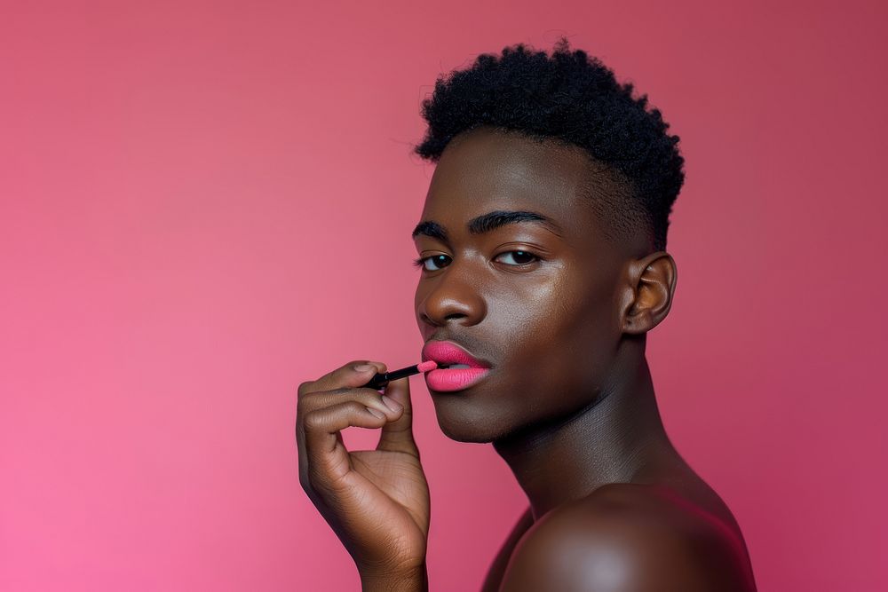 Black transgender male holding and apply pink lipstick with confident pose cosmetics person human.