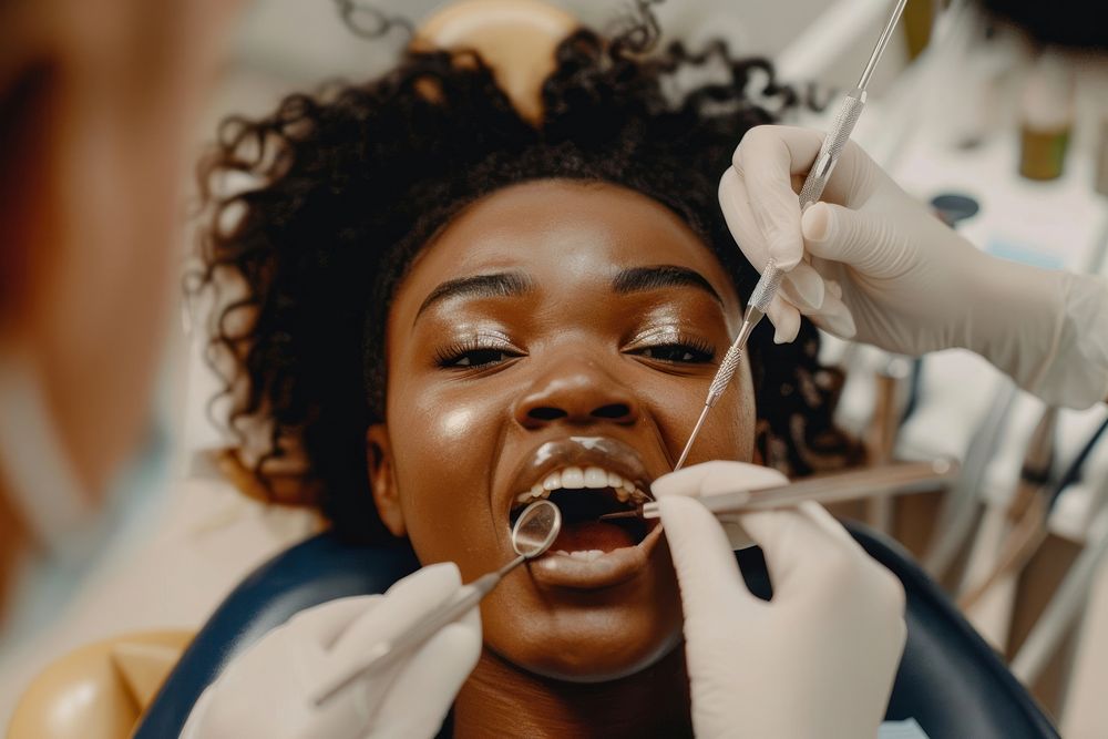 Black woman mouth open sitting on dentist chair and checking teeth toothbrush clothing apparel.