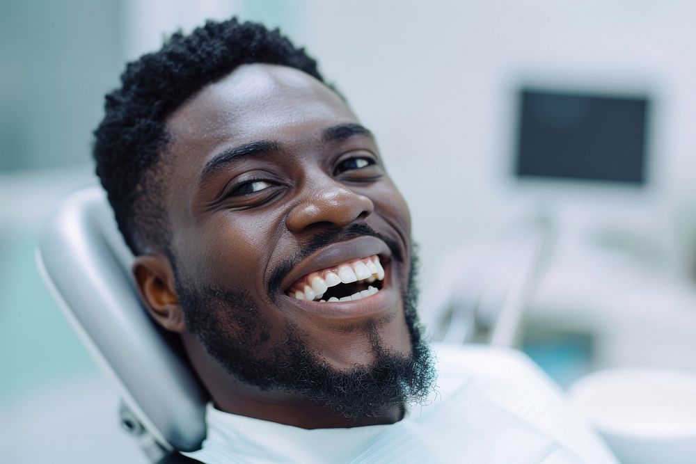 Black man mouth open sitting on dentist chair laughing dimples person.