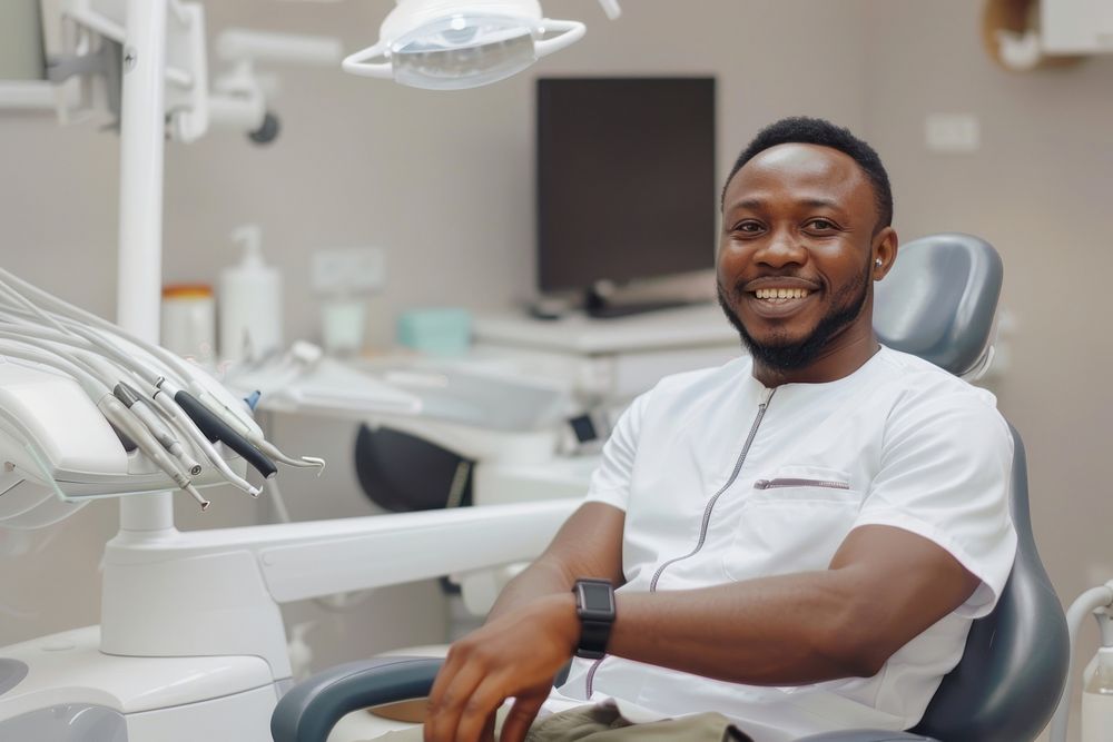 Black man smile sitting on dentist chair electronics wristwatch hardware.