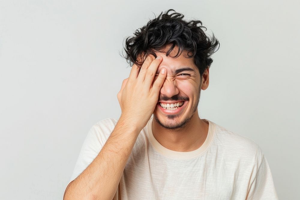 Man covering one eye with hand smile face laughing.