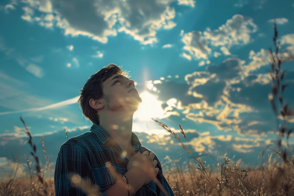 Young man holding cross photo sky sun.