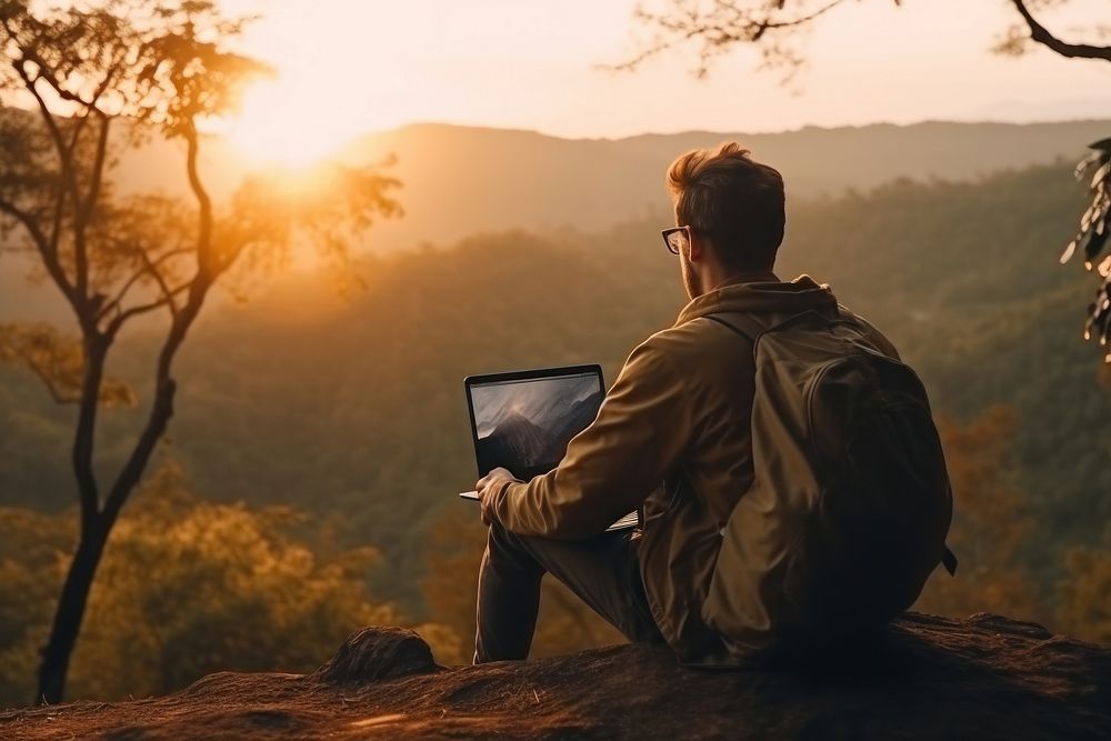 Young man sitting using laptop against scenery landscape forest backpacking electronics computer.