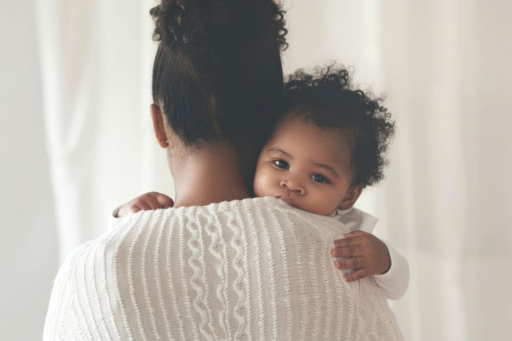 Caring biracial mother hold lean to chest cute little infant toddler hugging person human.