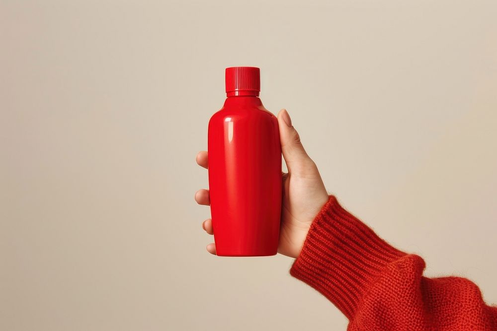Person holding red bottle cosmetics perfume water bottle.