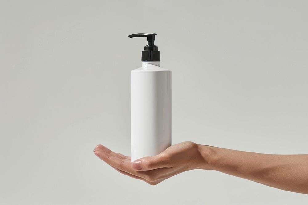 Hand hold white pump bottle lotion shaker.