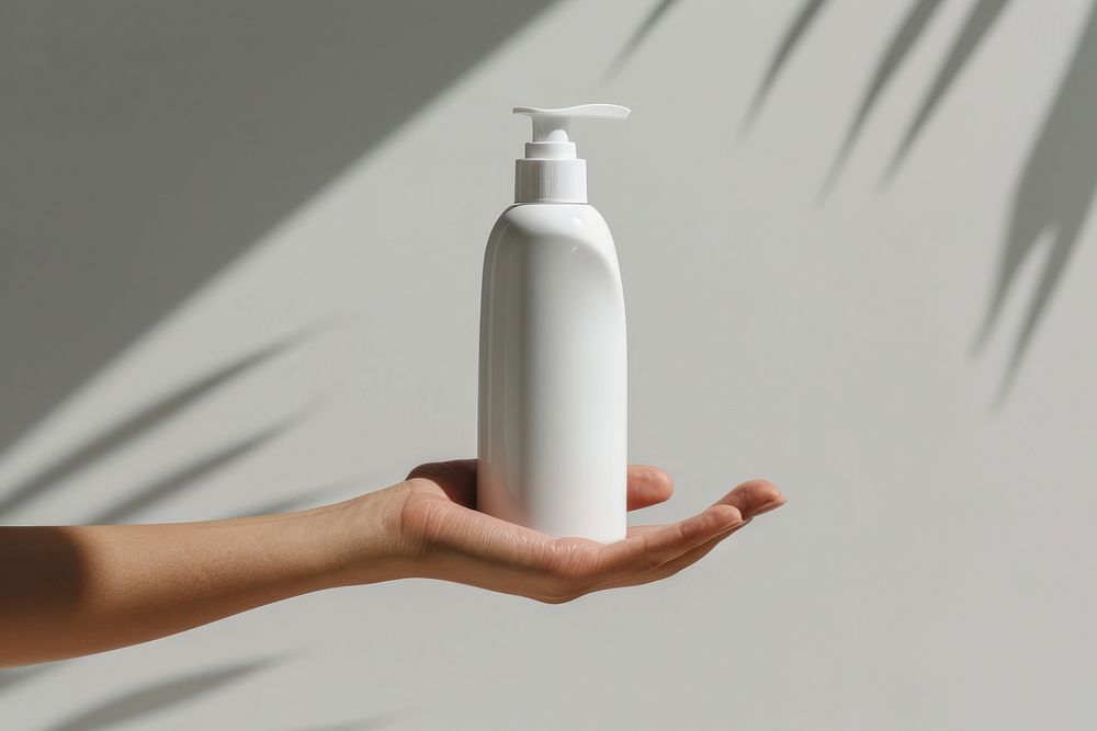 Hand hold white conditioner bottle lotion shaker.