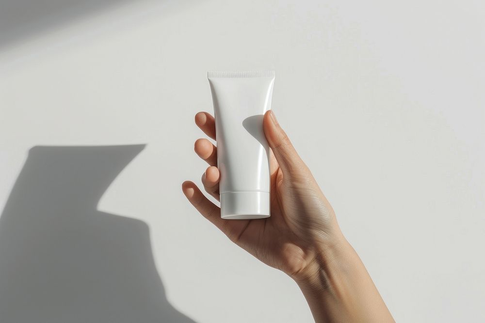 Hand hold white cosmetic tube cosmetics sunscreen bottle.