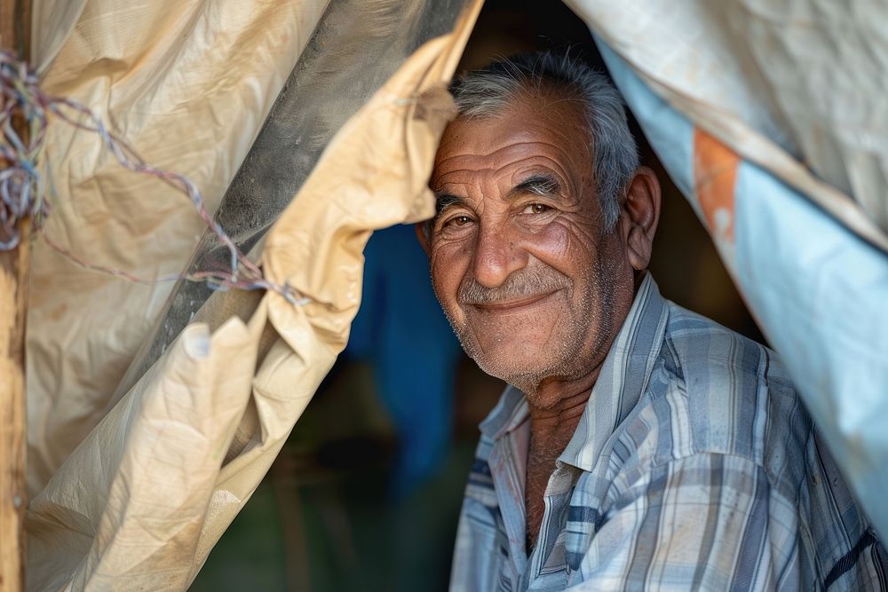 Refugee senior stands inside an old tent person human happy.