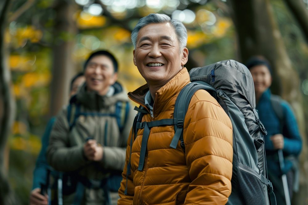 Smiling asian senior man hiking with friends backpacking laughing clothing.