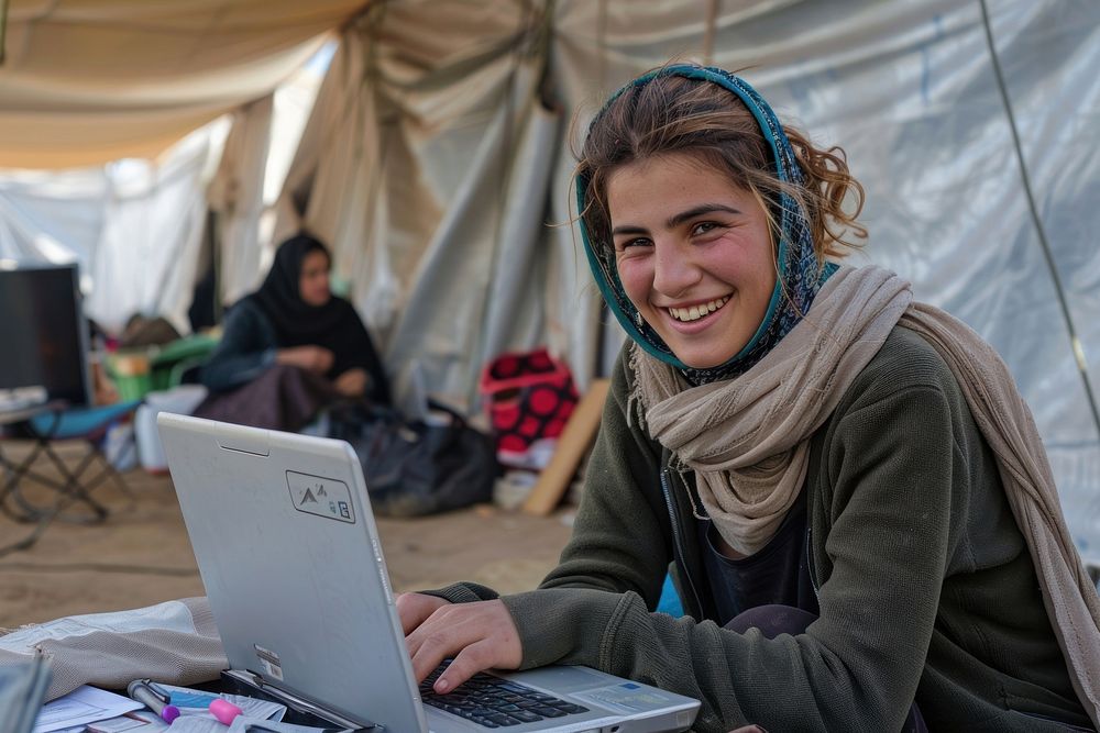 Smiling refugees studying online with laptop in large tents electronics accessories accessory.