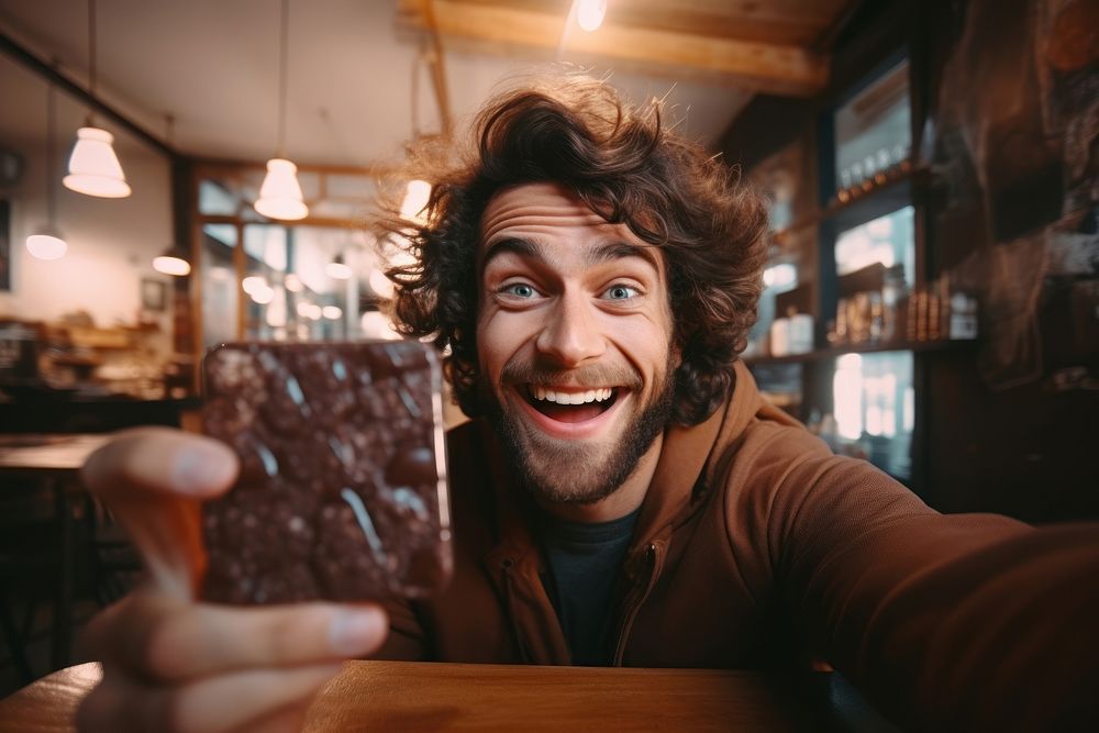 Eating chocolate bar selfie man surprised.