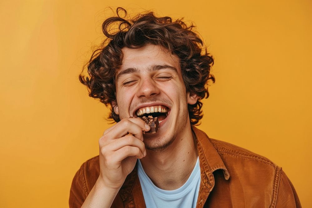 Happy young man eating chocolate laughing person biting.