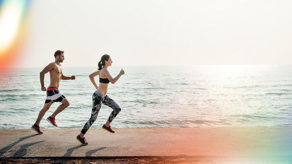 Healthy young couple running by the beach together