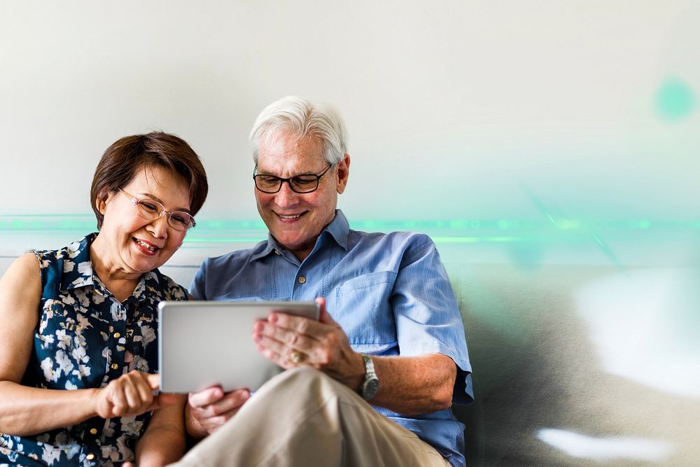 Senior couple using a digital device in a living room