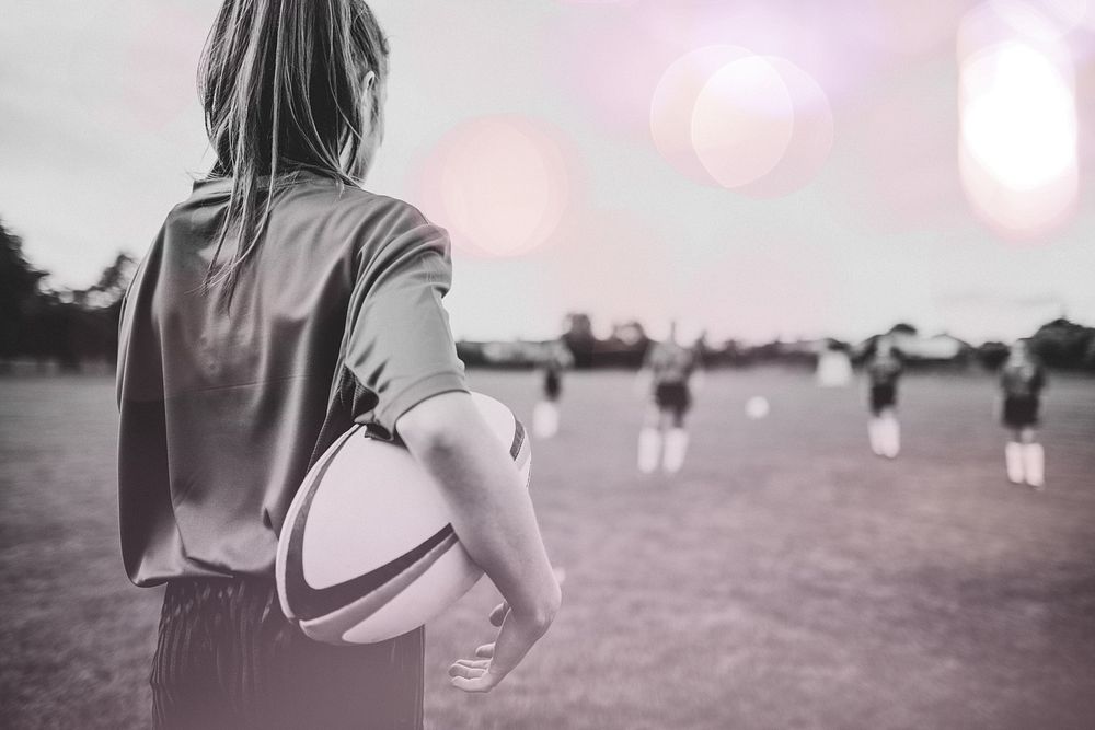 Female rugby player holding the ball in her arms