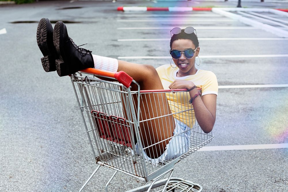An African Descent woman sitting in a shopping trolley