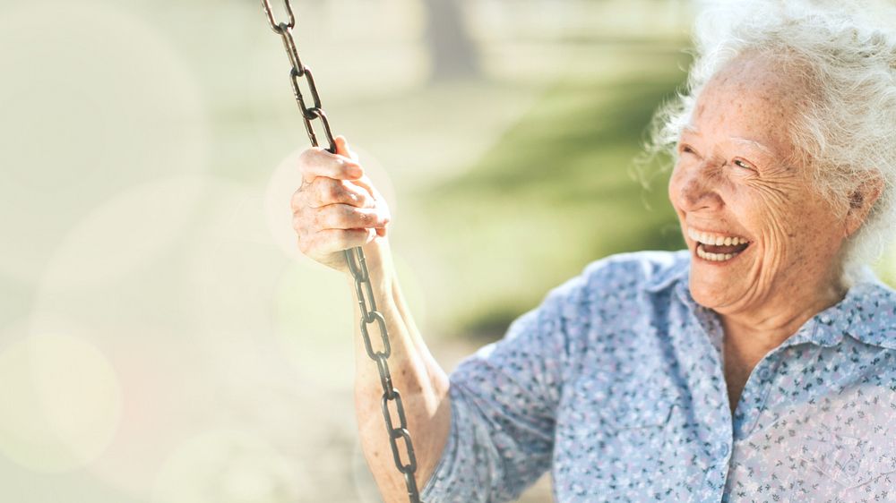 Cheerful senior woman on a swing at a playground