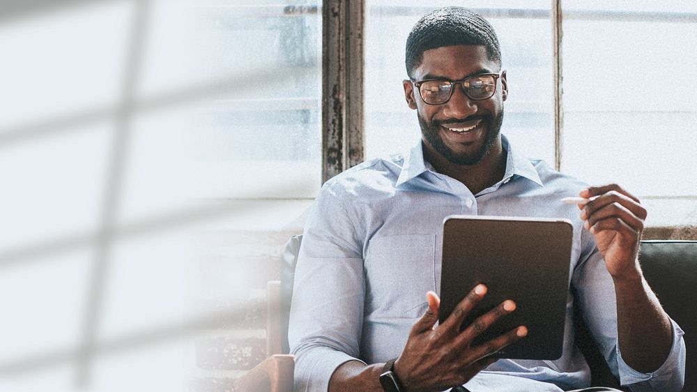 Cheerful black man using a stylus with a digital tablet in a living room
