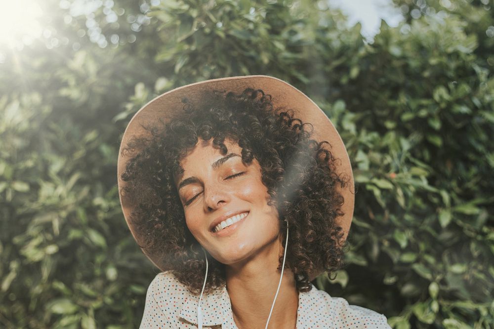 Beautiful woman listening to music in a botanical garden