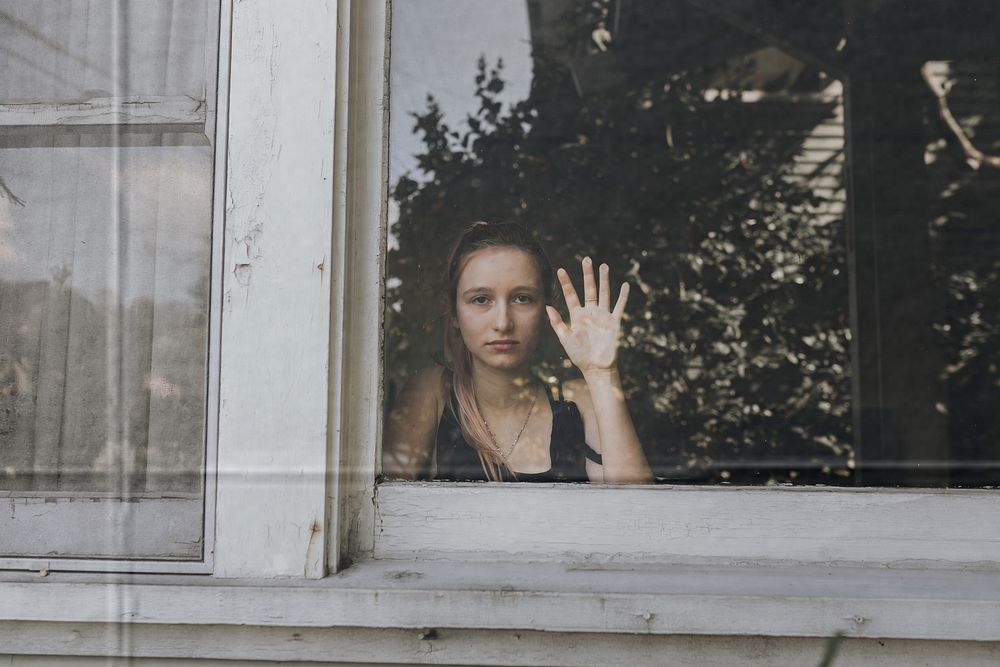 Girl looking out the window of her LA home during the covid-19 pandemic