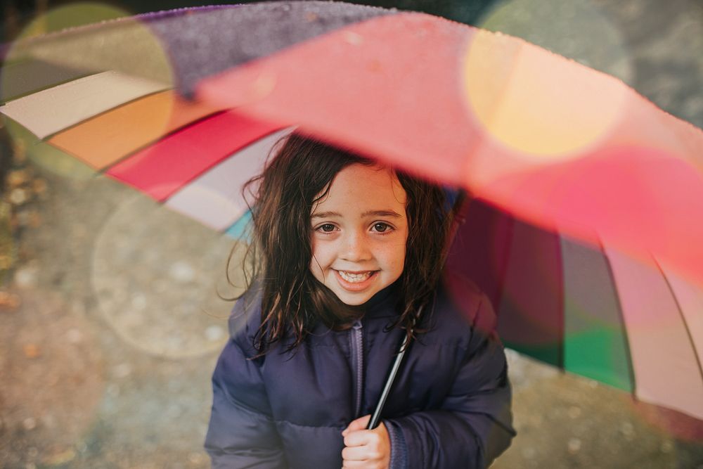 Little girl smiling with an umbrella while on a family trip outdoors portrait