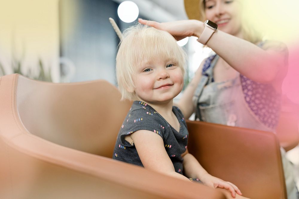 Hairstylist giving a haircut to an adorable blond kid