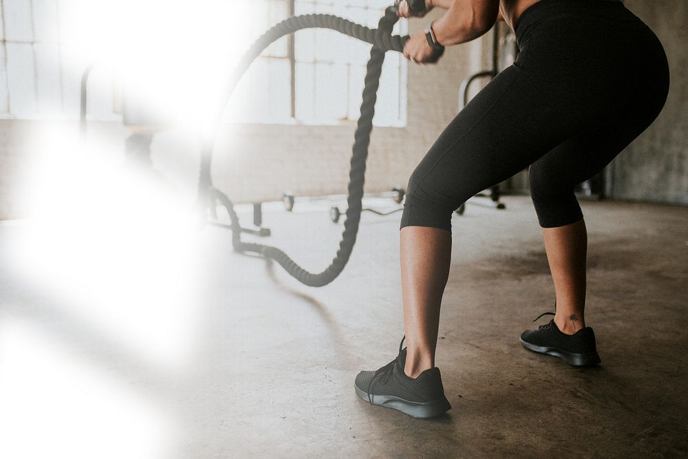 Sportive woman doing a battle rope in a gym