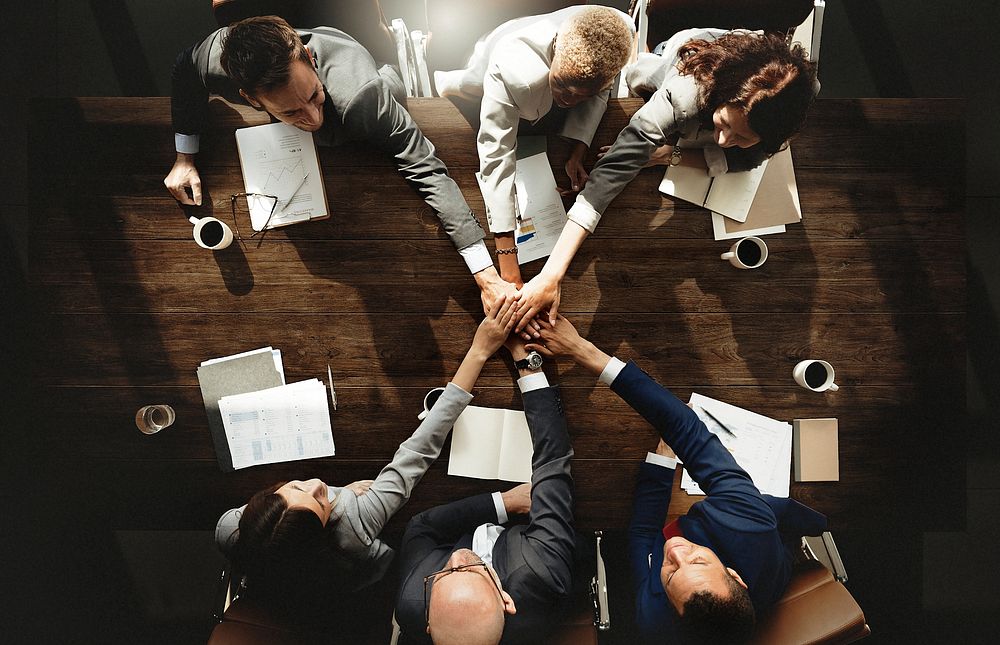 Diverse business people stacking hands together