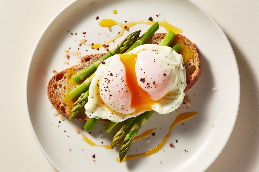 Poached egg on asparagus and avocado toast plate food.