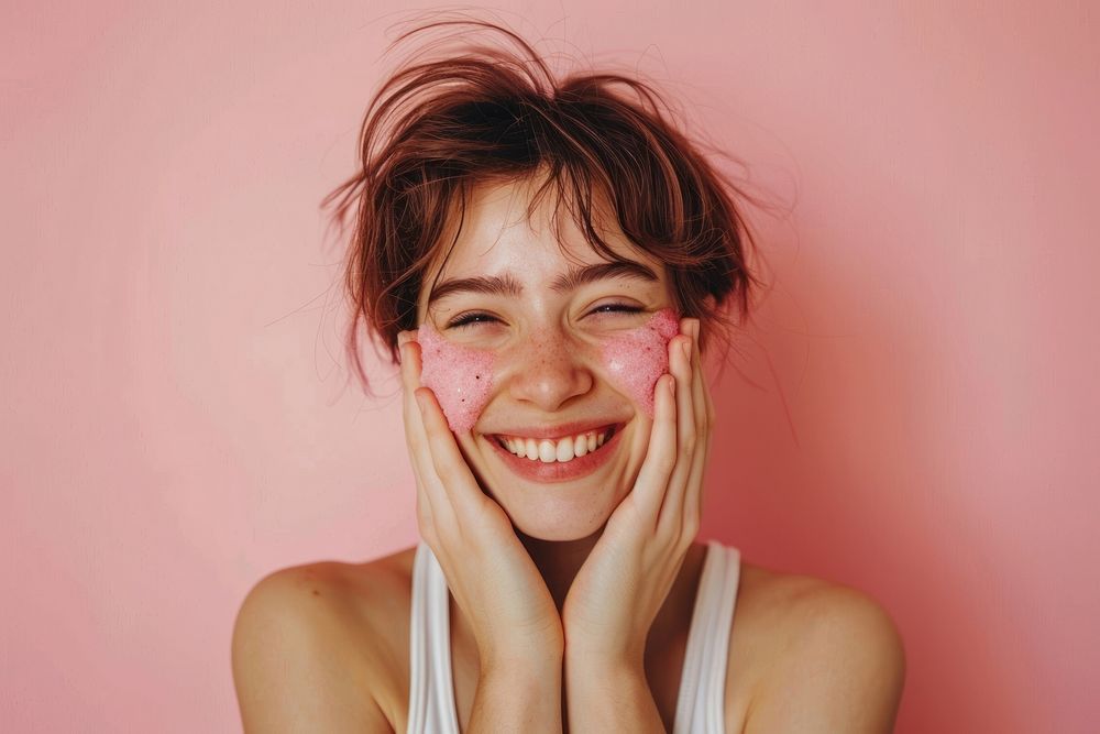 Girl short hair applying pink facial scrubb to both cheeks happy person female.