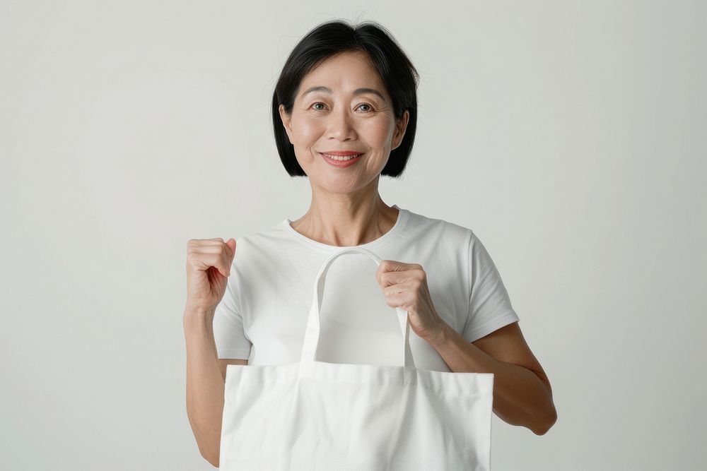Asian woman in 60s in white tee holding a white tote bag mock up female person adult.