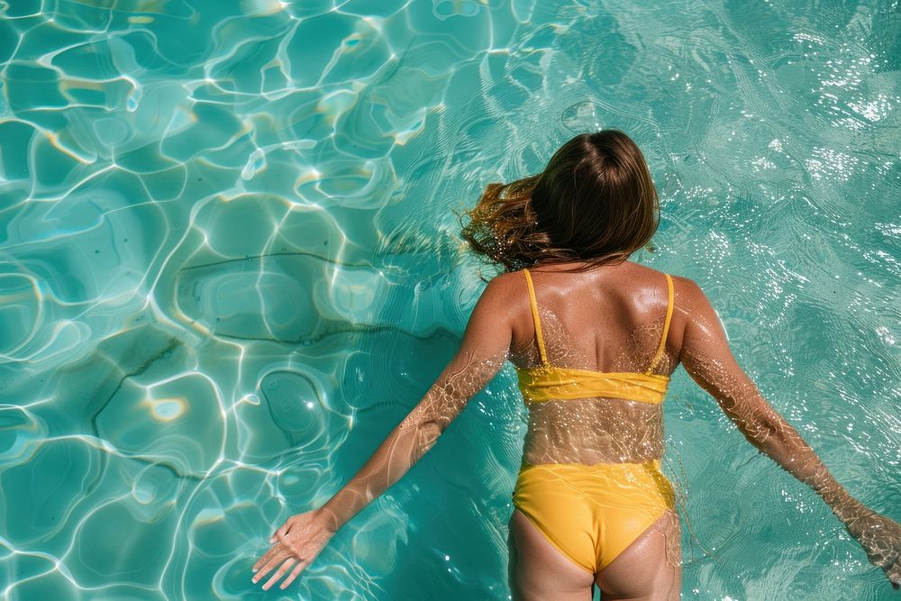 Yellow swimming suit floating on top of clear water summer recreation sunbathing.