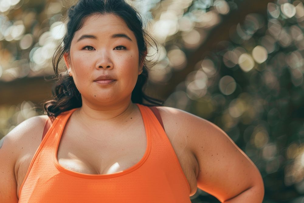 Asian chubby woman in brick orange activewear medication shoulder sweating.