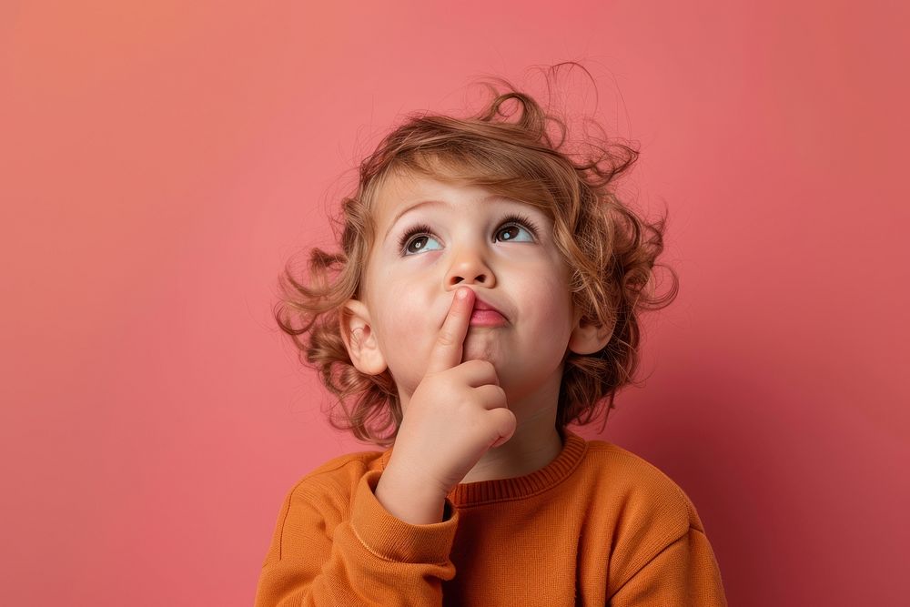 Curious child thinking against pink