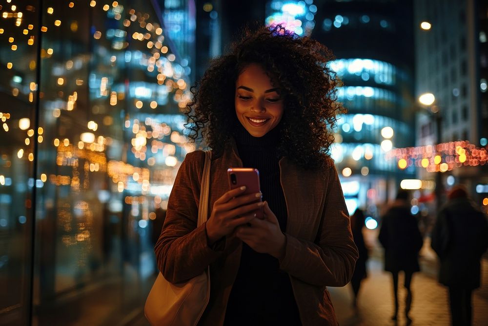 Young woman with curly hair uses her mobile phone reflection background smiling.