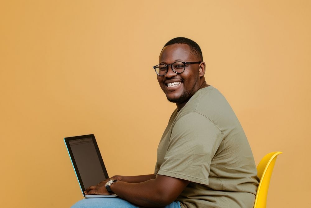 Man wearing glasses smile to a camera with a laptop man background sitting.