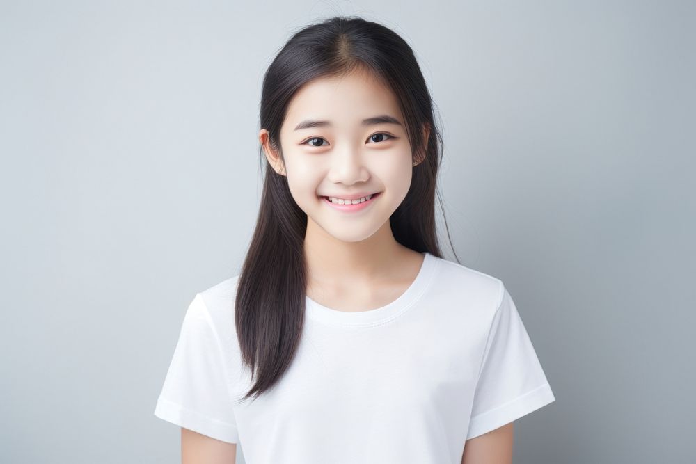 A young asian girl wearing a white T-shirt smiling female happy.