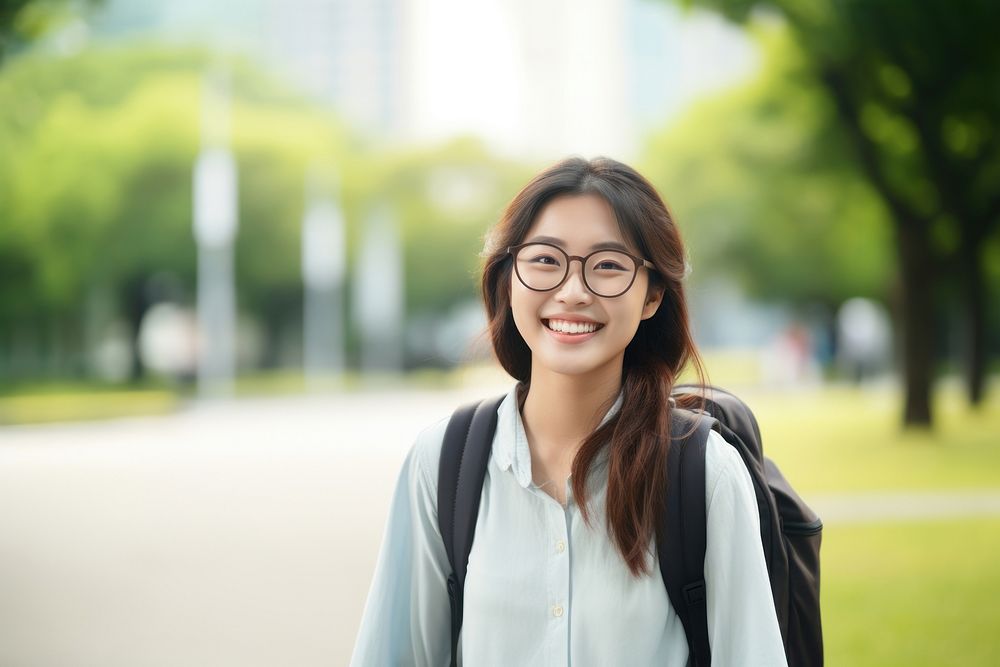 Smiling young asian woman student wearing glasses and casual background clothing backpack.