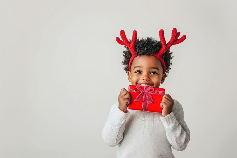 A Happy little african american boy wearing red deer antlers christmas sweater white.